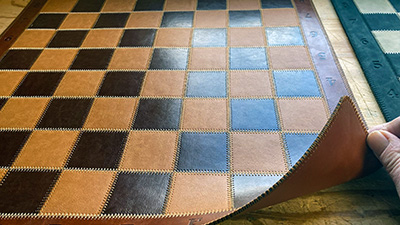 The brown and tan leather chessboard is still thick but not as much as the black and white one